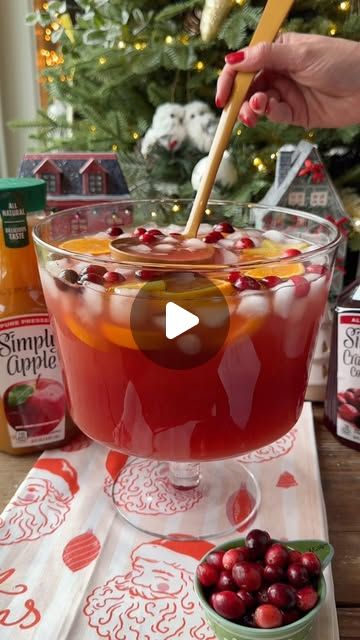 a bowl of cranberry apple cider punch on a table with a christmas tree in the background