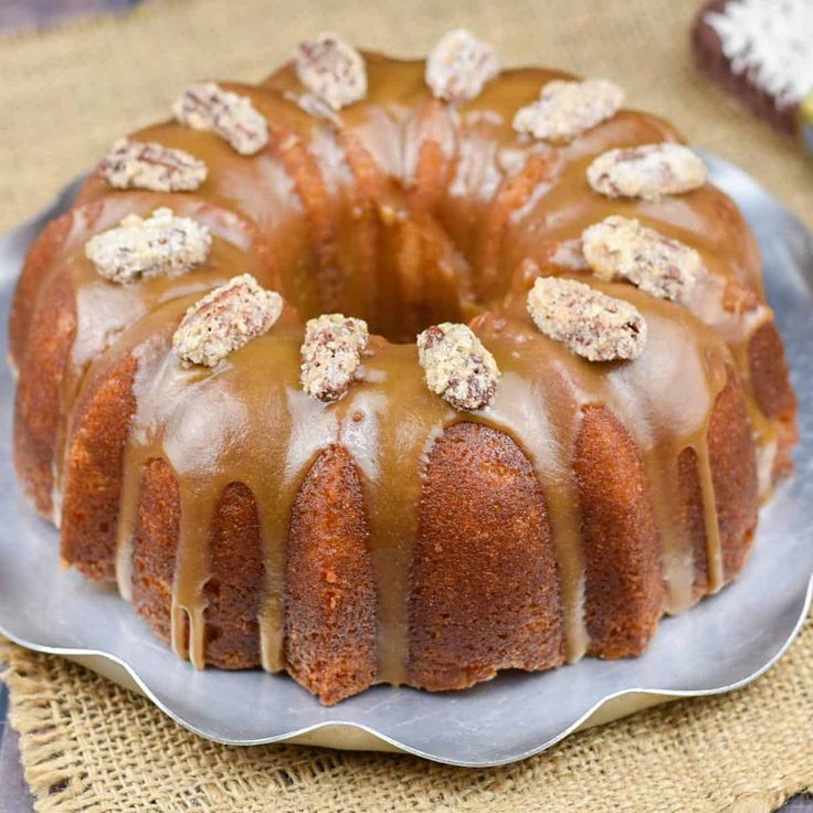 a bundt cake with frosting and nuts on top, sitting on a plate