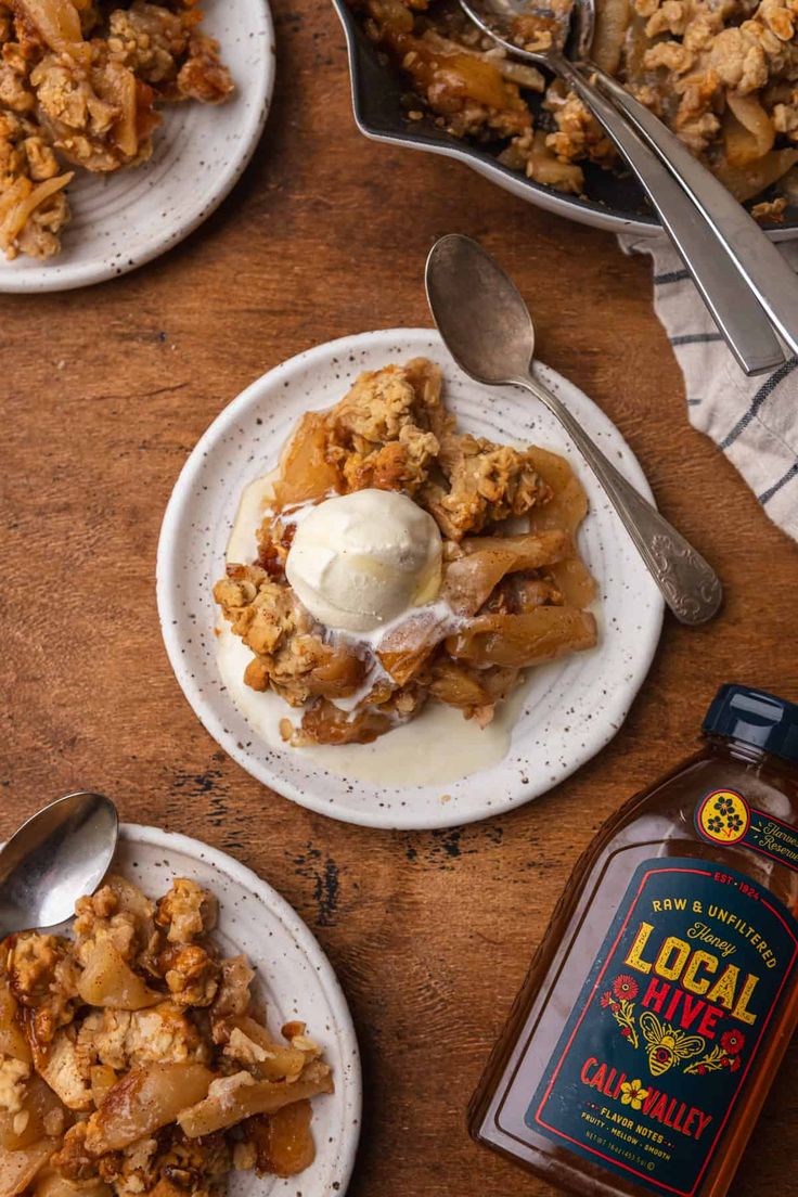 apple crisp with ice cream on top and caramel syrup next to it, sitting on a wooden table