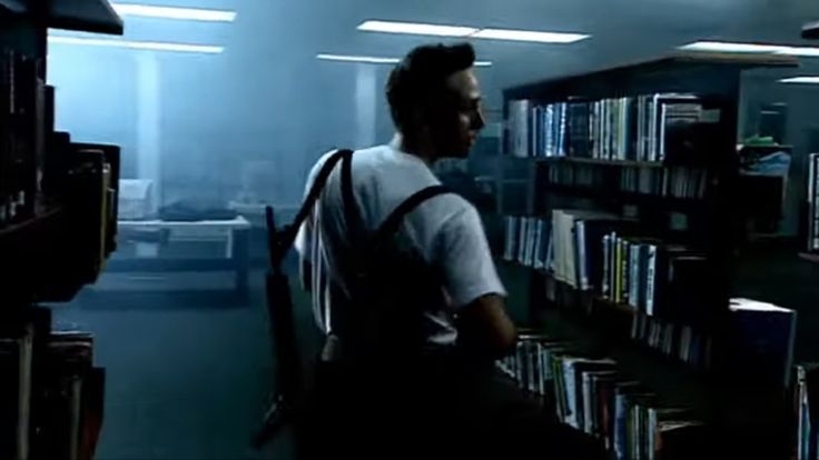 a man sitting in front of a book shelf filled with books