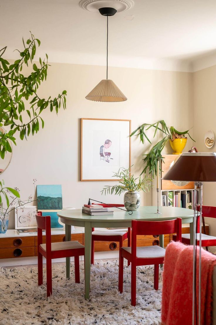 a dining room table and chairs with plants in the corner