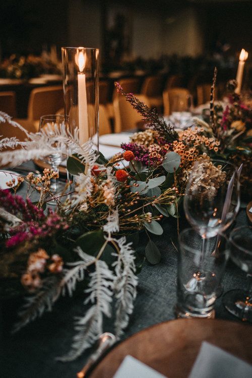 the table is set with candles, flowers and greenery for an elegant wedding reception