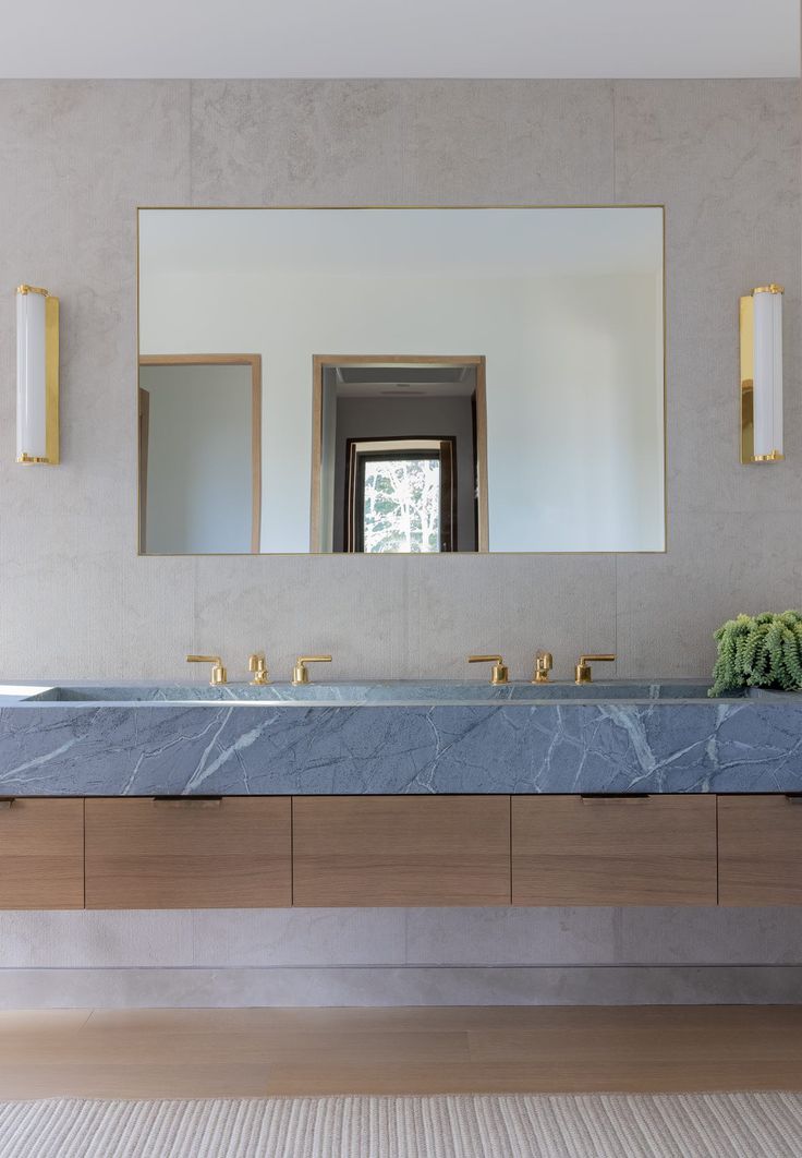 a bathroom with marble counter tops and gold faucets on the wall, along with two sinks