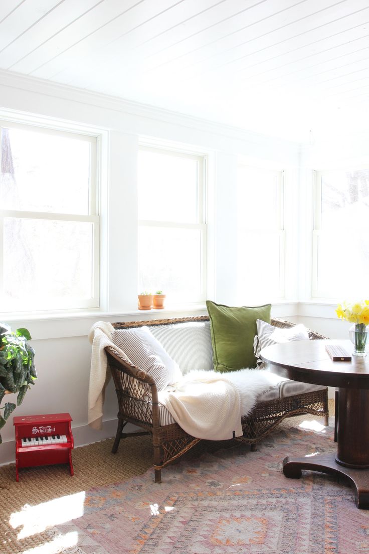 a living room filled with furniture and a table in front of two windows on top of a rug