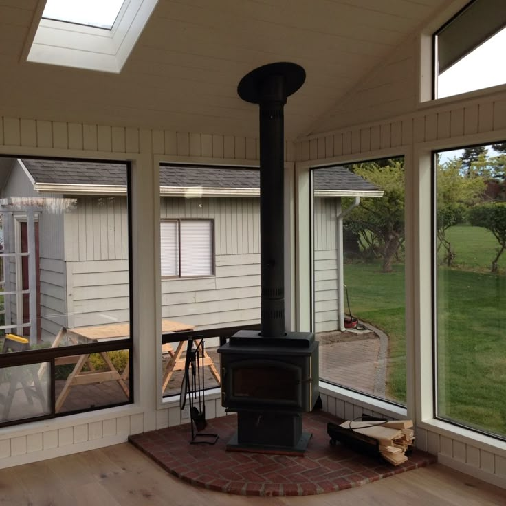 an open room with a wood stove in the center and large windows on both sides