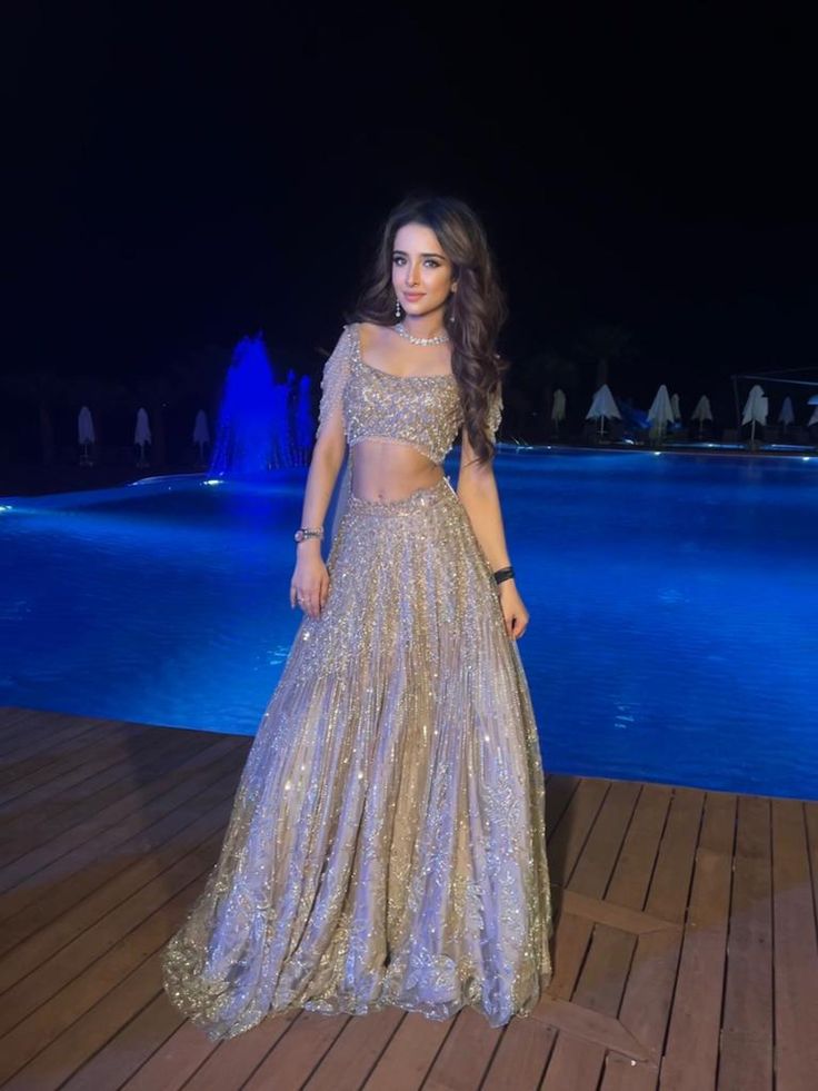 This lehenga set is hand embroidered with all-over sequin, crystal, and cutdana work on a nude gold net base. Paired with a crystal-embellished cold shoulder blouse with tassel detailing and an attached drape.DELIVERY TIMEPlease allow 8-12 weeks for your outfit to arrive.FABRIC DETAILSNetProfessional cleaning only. Glamorous Hand Embellished Semi-stitched Lehenga, Glamorous Hand Embellished Choli For Festive Season, Hand Embellished Glamorous Lehenga, Glamorous Hand Embellished Festive Choli, Glamorous Festive Hand Embellished Choli, Glamorous Hand Embellished Choli For Reception, Evening Party Wear Hand Embellished Choli, Evening Party Wear Choli Hand Embellished, Glamorous Semi-stitched Hand Embellished Choli