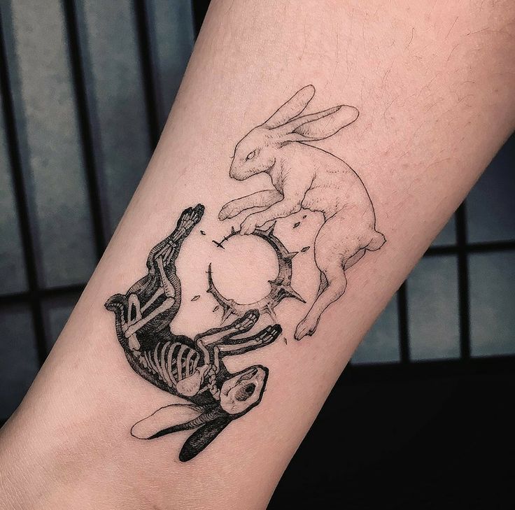 a tattoo on the leg of a person with a rabbit and skeleton in front of them