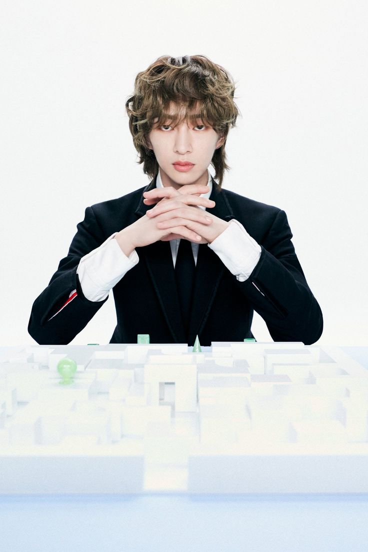 a man in a suit sitting at a desk with his hands folded over his face