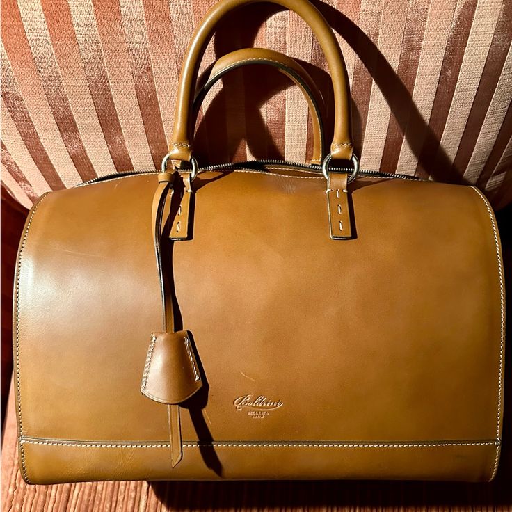 Nwt - Never Used - Boldrini Selleria Satchel Handbag. The Bag Measures 13” L X 10” H X 8 1/2” D. It Is Made Of Vacchetta / Calfskin Leather In Beautiful, Rich Camel Color. There Are Leather Side Gussets With A Full Two-Ended Zipper Opening At Either End. Gold Tone Hardware. This Is A Arm / Handbag. No Shoulder Strap. **Please Note** The Bag Has Two Minor Scratches Near Id Tag - Please See Photo. Possibly Occurred During Shipment - Does Not Detract From The Handbag. The Interior Has A 100% Red Co Brown Briefcase With Top Handle And Dust Bag, Top Handle Brown Travel Bag With Dust Bag, Elegant Travel Satchel In Cognac, Classic Brown Satchel For Everyday Luxury, Elegant Cognac Satchel For Travel, Elegant Cognac Briefcase With Top Carry Handle, Luxury Cognac Satchel Travel Bag, Classic Cognac Tote Travel Bag, Classic Cognac Travel Tote Bag