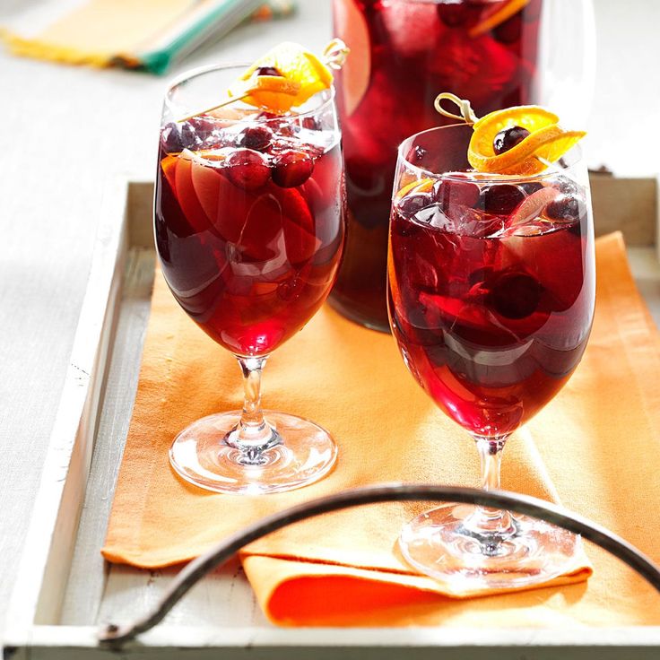 three glasses filled with red liquid sitting on top of a wooden table next to a plate