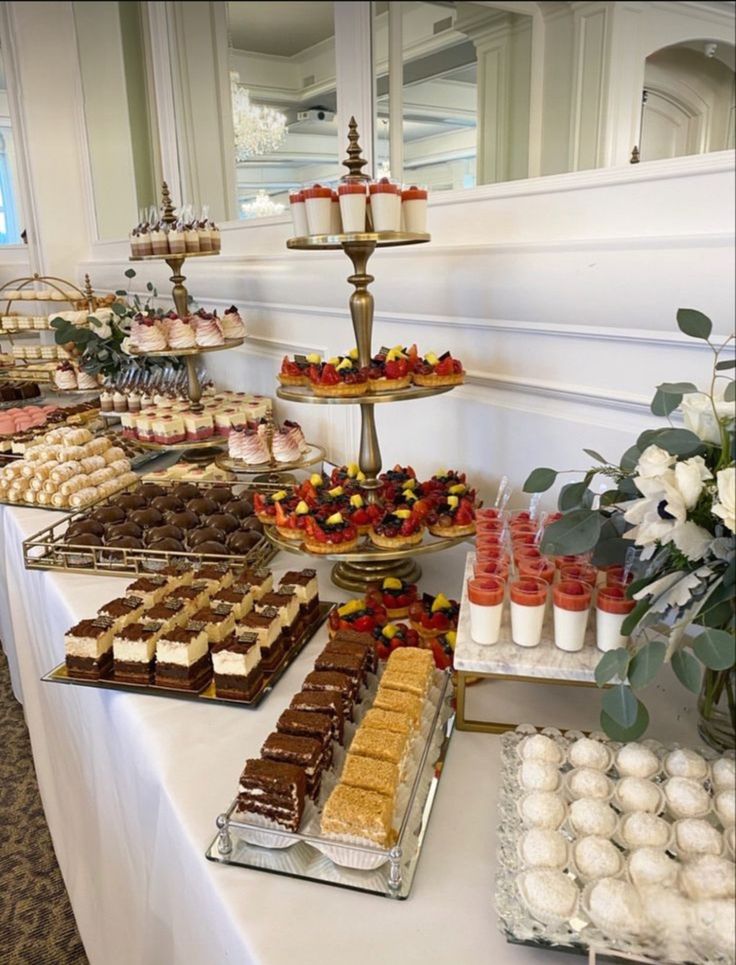 an assortment of desserts and pastries on a long table in a banquet hall