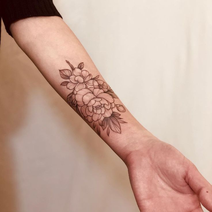 a woman's arm with a flower tattoo on the left side of her hand