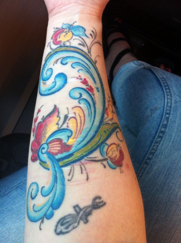 a person with a colorful tattoo on their arm and wrist is holding a cell phone