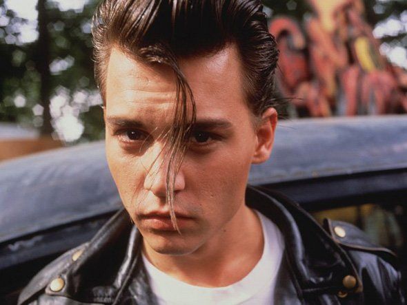 a man in a leather jacket standing next to a car