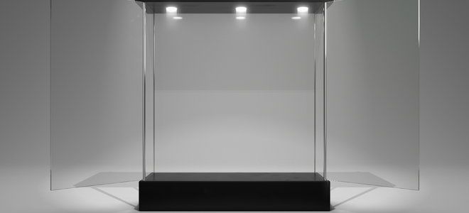 a black and white photo of a glass display case with lights on the top shelf