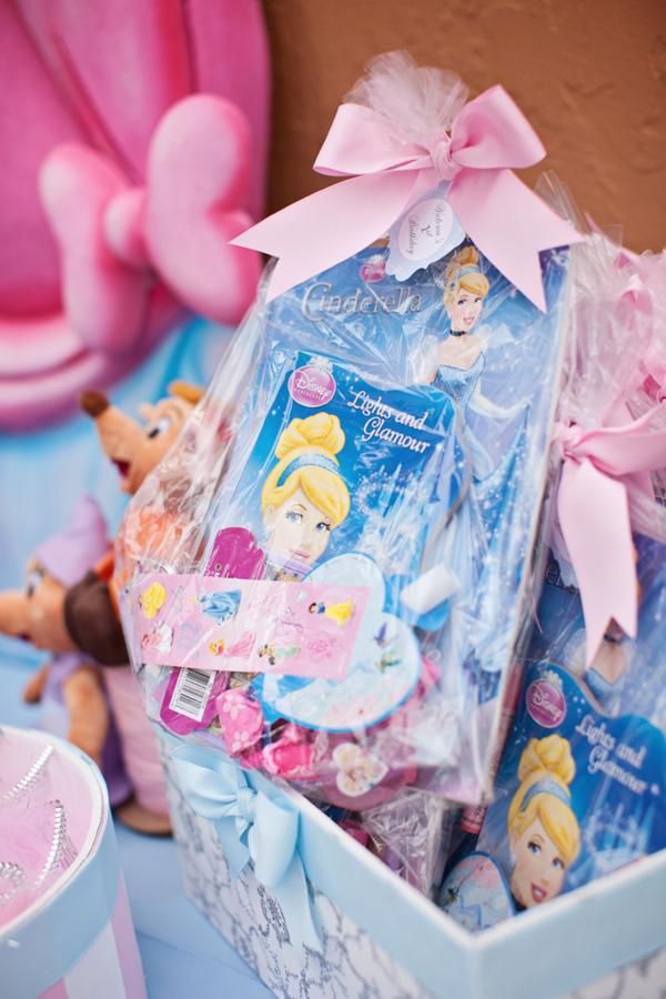 a box filled with princess dolls and other toys next to a pink heart shaped cake