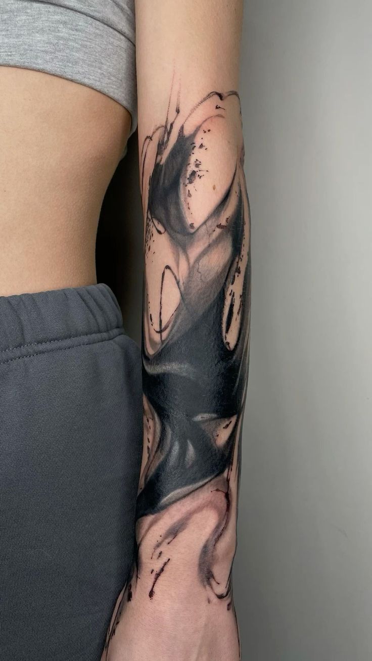 a woman's arm with black and grey ink art work on her left arm