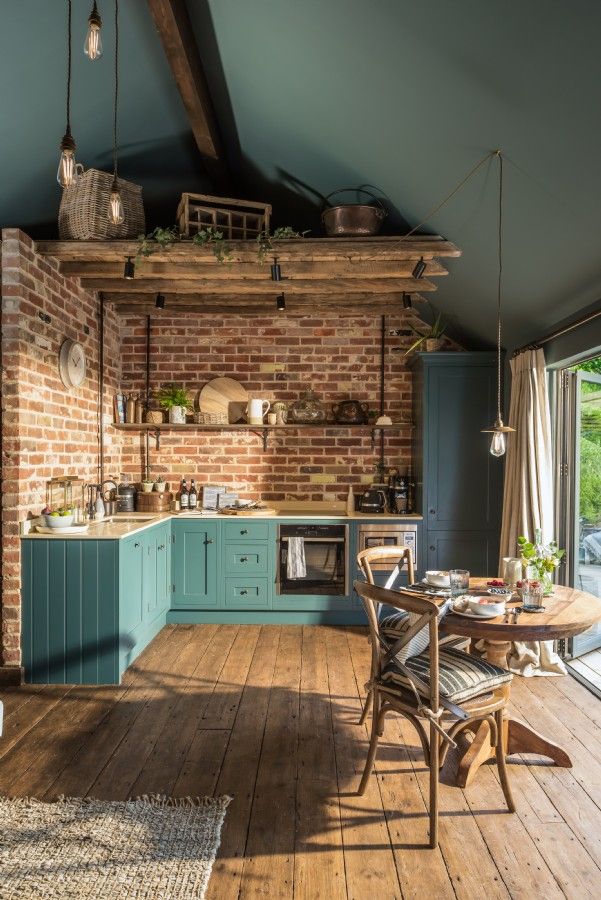 an open kitchen and dining area with brick walls, wood floors and blue painted cabinets