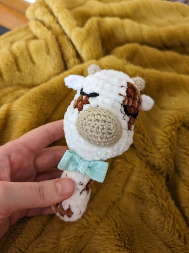 a hand is holding a stuffed animal that looks like a sheep