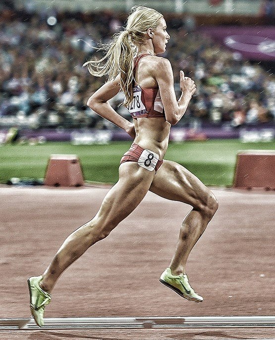 a woman running on a track in front of a crowd