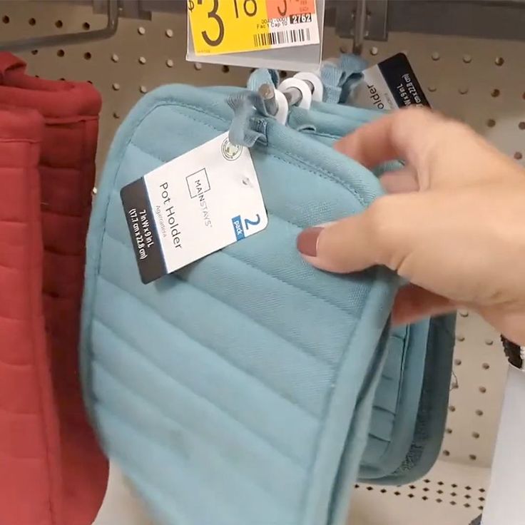 a person holding onto a blue case with price tags on it in a store shelf