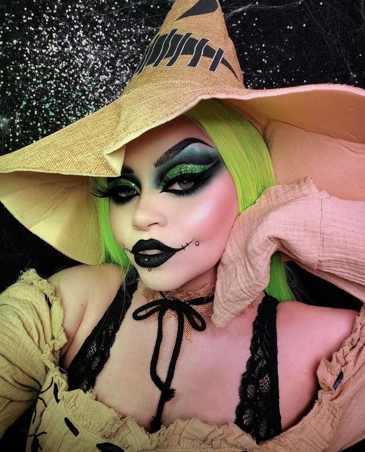 a woman with green hair and makeup wearing a witches hat, black eyeliners