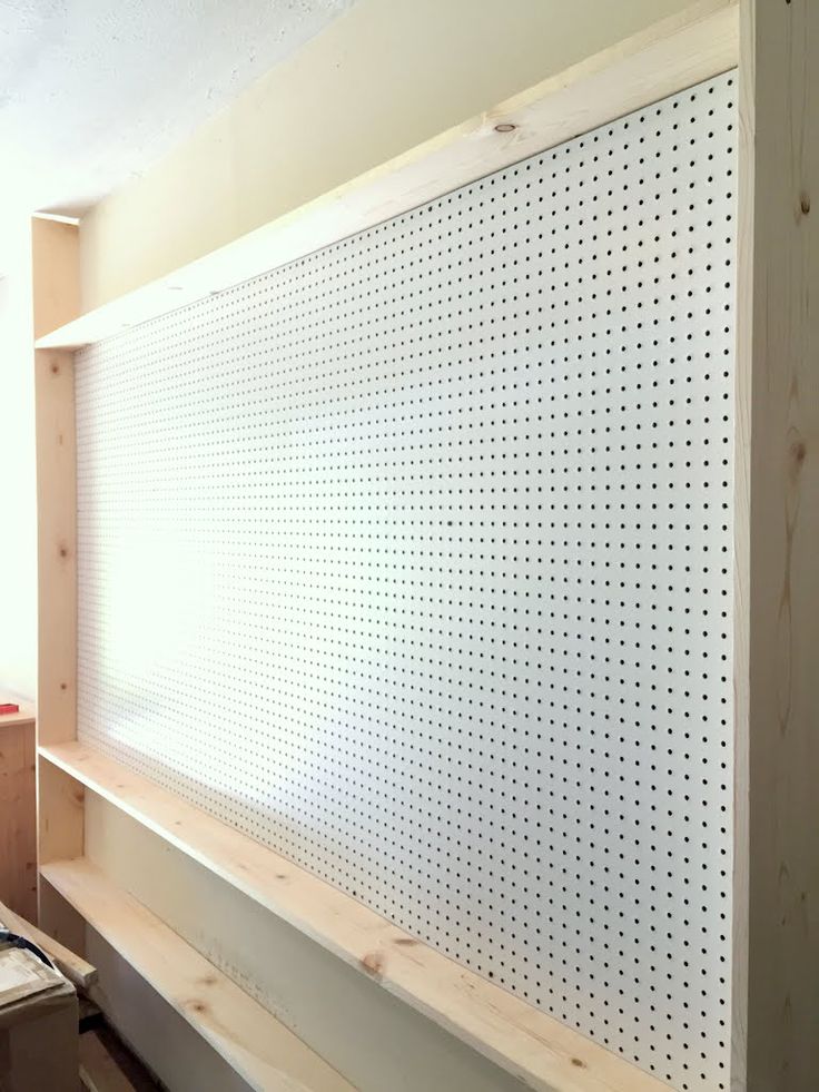 a white pegboard mounted to the side of a wall in a room with wooden shelves