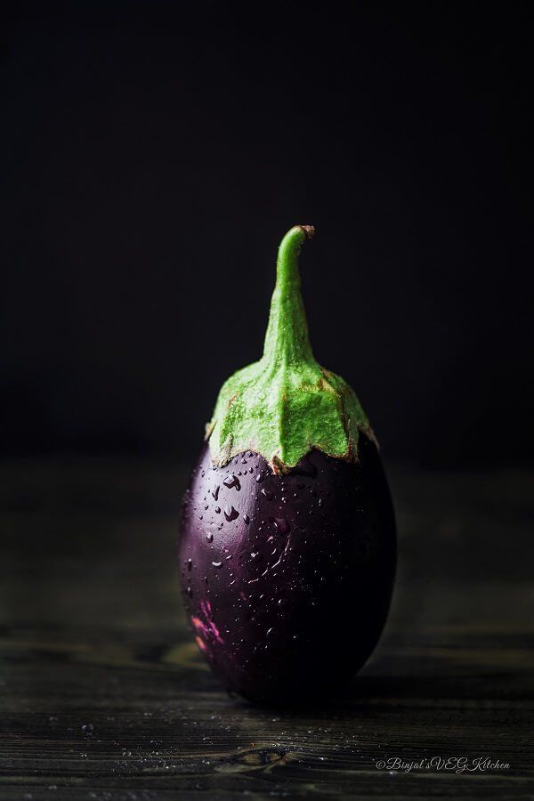 an eggplant on a wooden table with water droplets