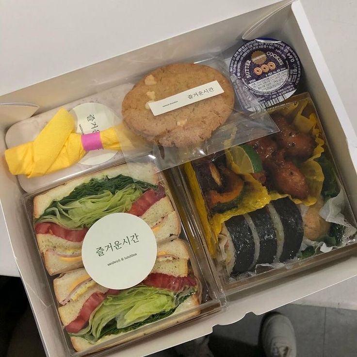 an open lunch box with sandwiches and other food items in it, including breads