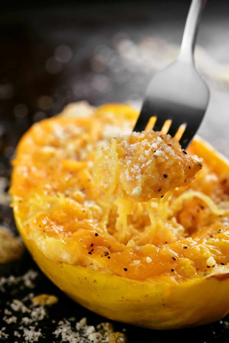 a fork is stuck into an uncooked spaghetti dish with cheese and bread crumbs