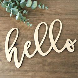 the word hello spelled in wooden letters on a table next to eucalyptus leaves and a potted plant