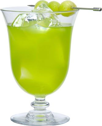 a glass filled with green liquid and limes