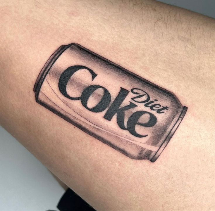 a black and white photo of a can of coke tattoo on the right thigh, which reads diet coke