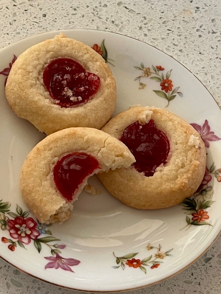 two jelly filled cookies on a floral plate