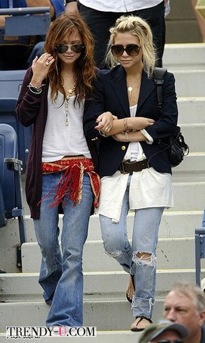 two women are walking down the steps at a baseball game, one is holding her hand up to her ear