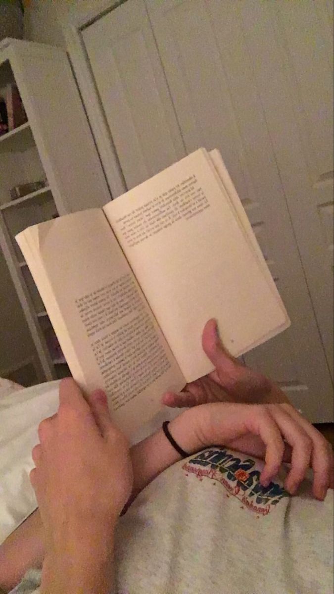 a man laying in bed reading a book