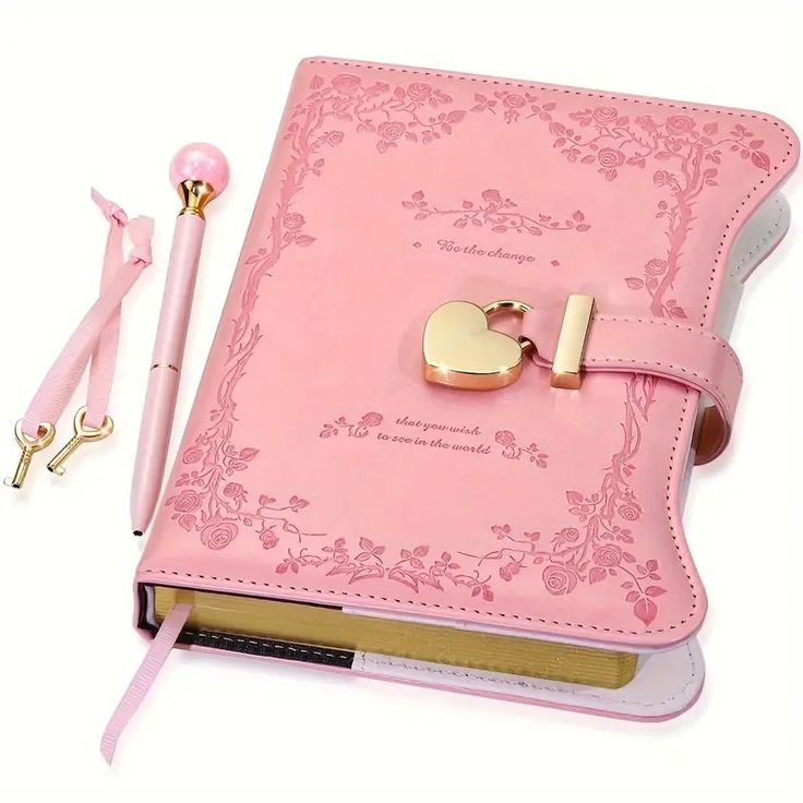 a pink book with a gold heart on it and a pair of scissors next to it