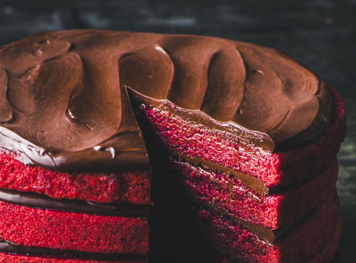 a red velvet cake with chocolate frosting and a slice cut out from the side