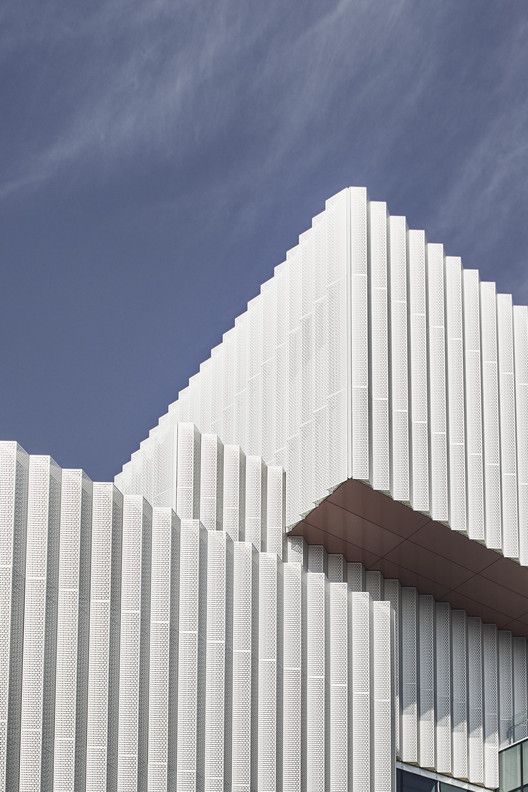 an architectural building with white lines on the side and blue sky in the back ground