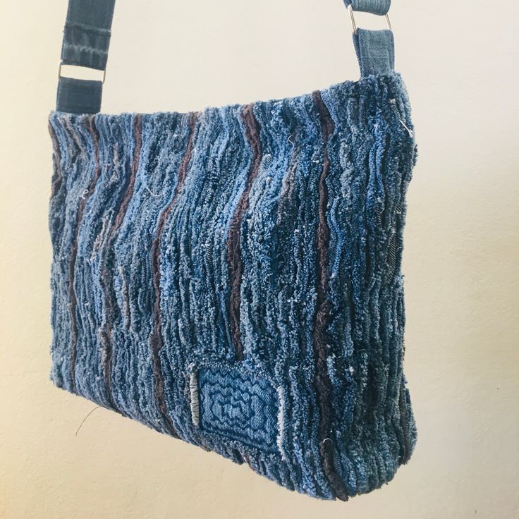 a blue purse hanging from a hook on a wall with white walls in the background