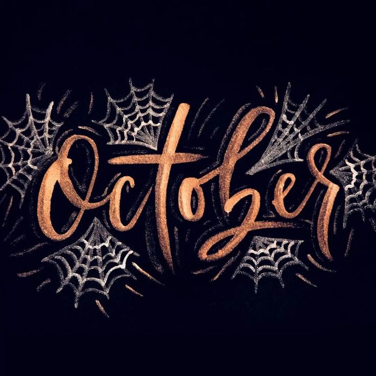 the word october written in chalk on a black background with cobwes and spider web