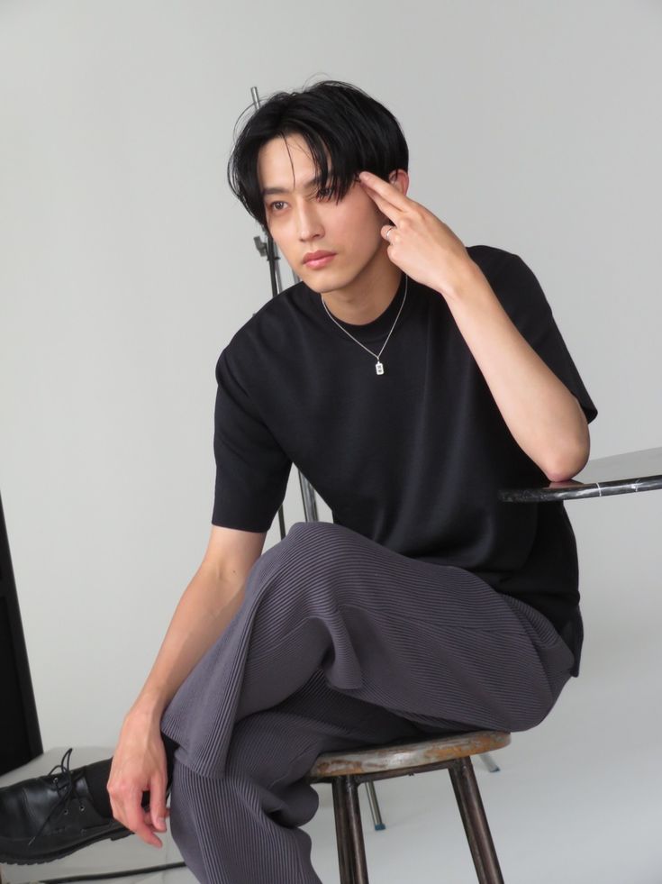 a young man sitting on top of a stool next to a computer monitor and keyboard