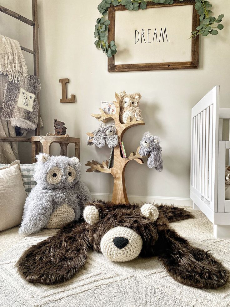 two stuffed animals sitting on the floor next to a baby crib