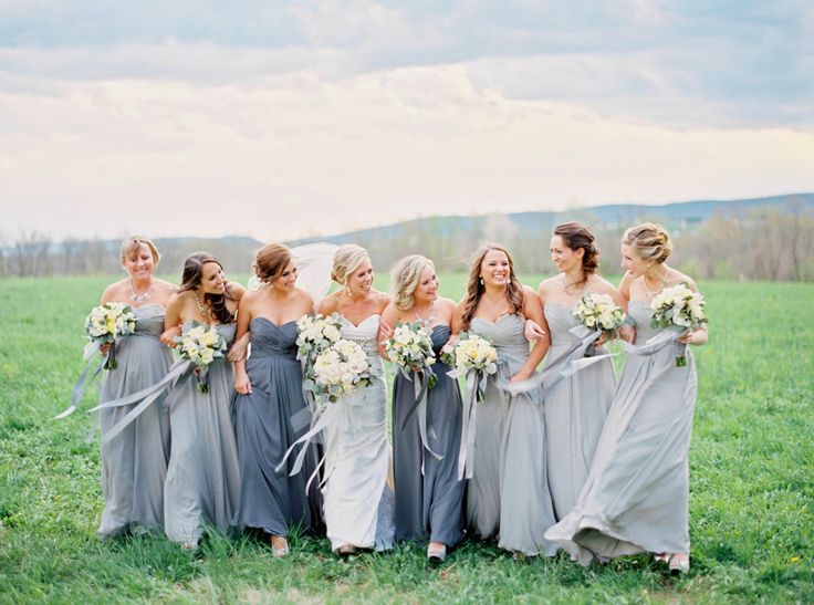 a group of women standing next to each other on top of a green grass covered field