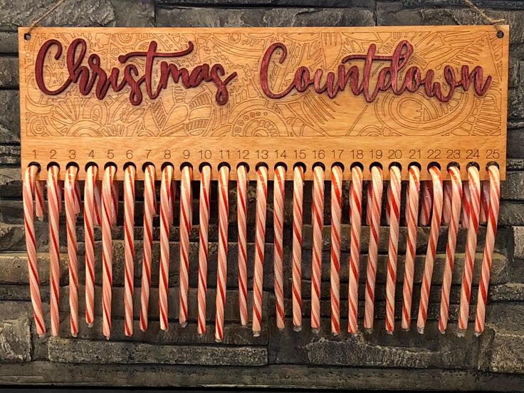 a wooden sign with candy canes hanging from it's sides in front of a brick wall