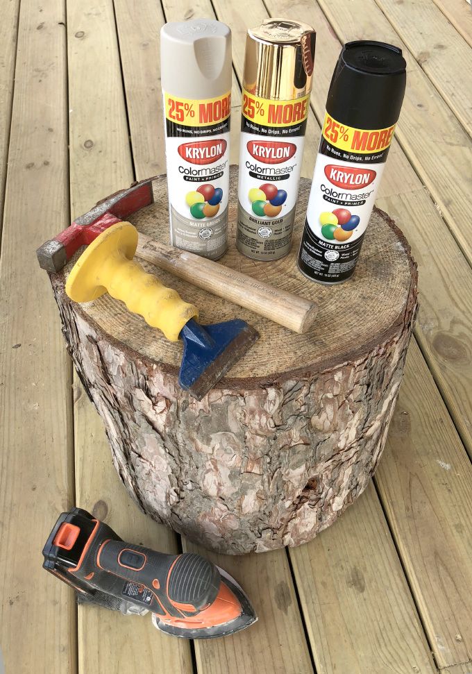 some paint and tools are sitting on top of a tree stump