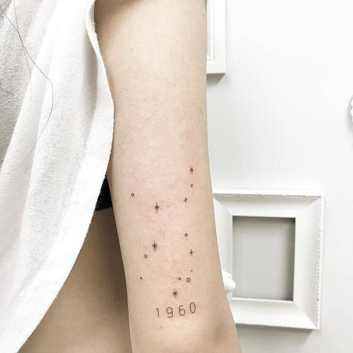 a woman's arm with numbers and stars tattooed on the back of her left arm