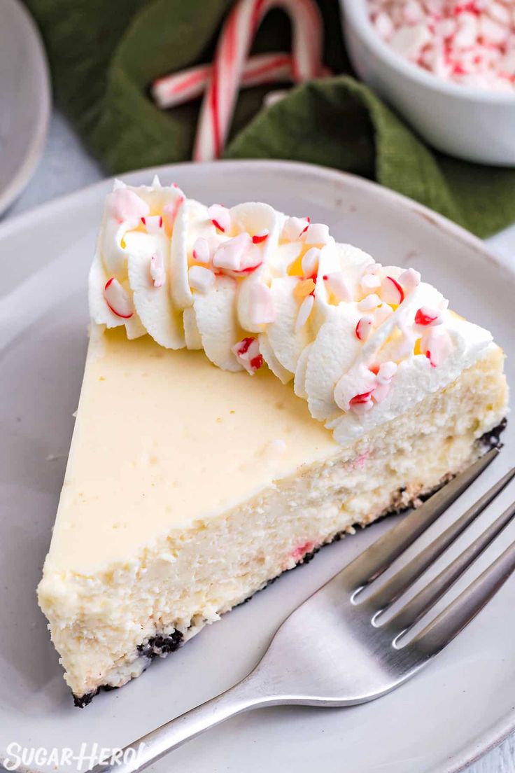 a slice of cheesecake with whipped cream and candy canes is on a plate