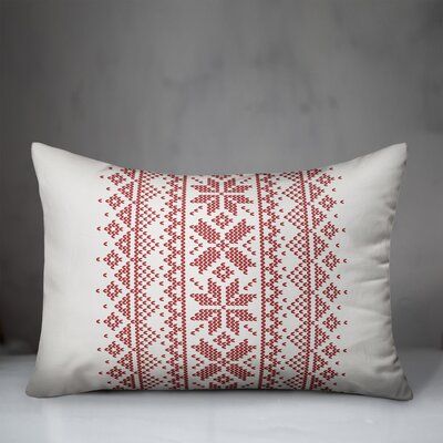 a red and white embroidered pillow sitting on top of a bed next to a wall