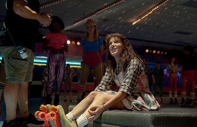 a woman sitting on top of a bench next to a bunch of people in the background